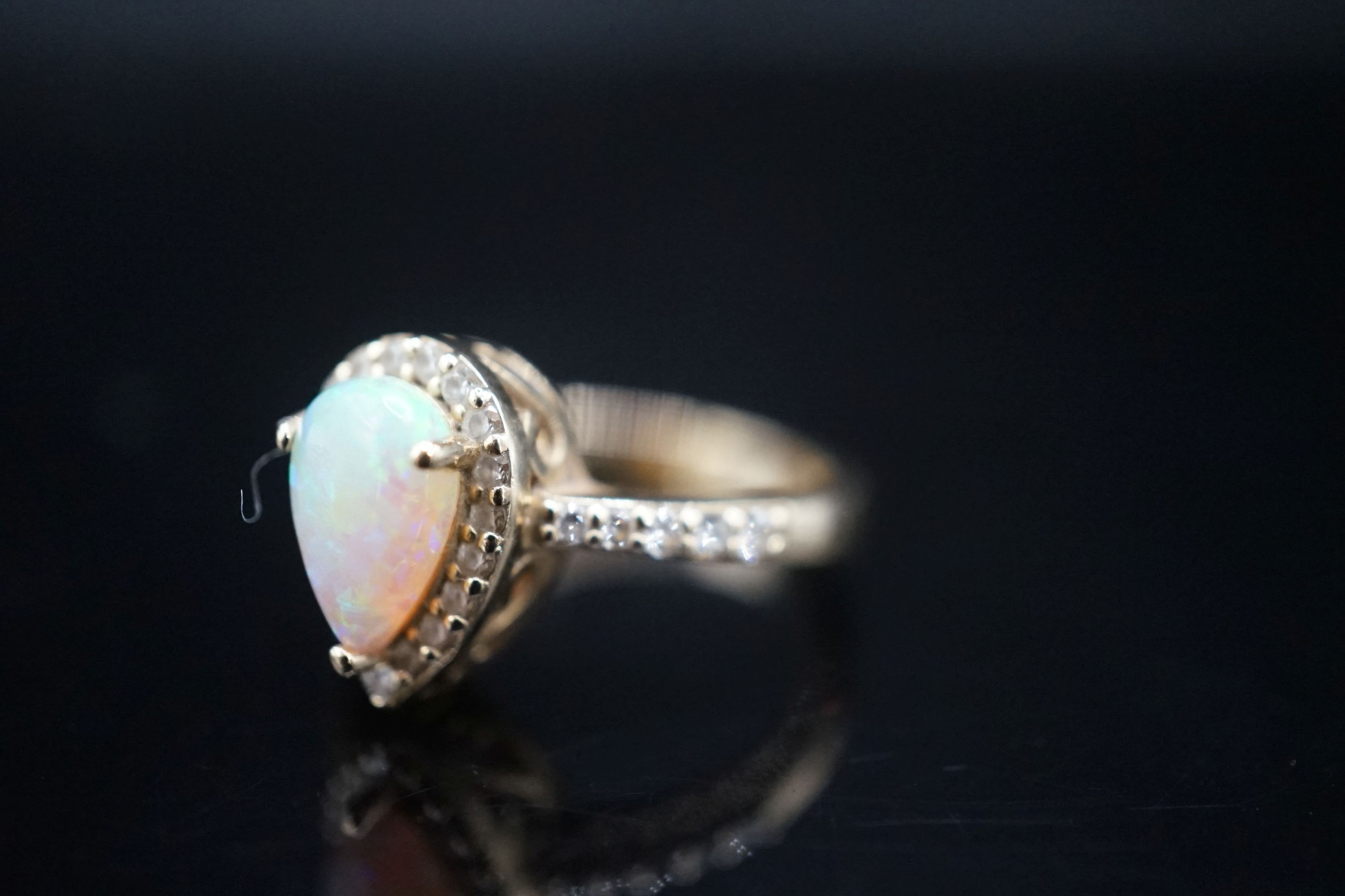 A modern 14k yellow meta, white opal and diamond set pear shape cluster ring, with diamond set shoulders, size K, gross weight 4.3 grams.